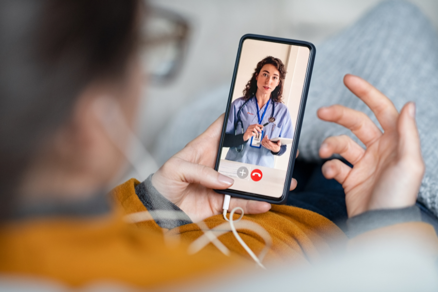 una persona sostiene una videollamada, en la pantalla del teléfono se ve una médica dando instrucciones